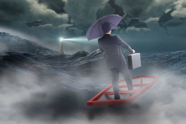 Businessman in boat with umbrella against stormy sea with lighthouse