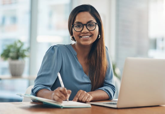 Portrait of a young businesswoman writing notes while working in an office