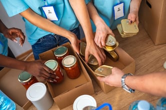 an aerial shot of several volunteers collecting non-perishable items in cardboard boxes.