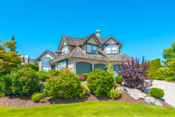 Image of a beautiful large home, with a large, lush, green garden covering the lawn.